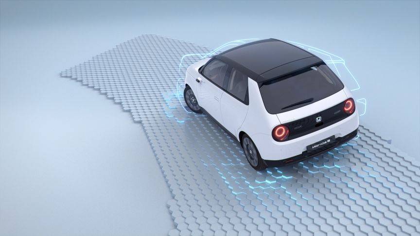hintere Luftaufnahme des weißen Honda E Elektroautos, das auf simulierter Straße fährt