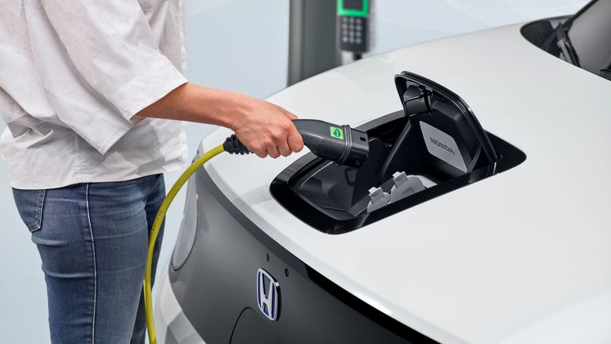 Nahaufnahme einer Frau, die Ladekabel in Honda E Elektroauto einsteckt
