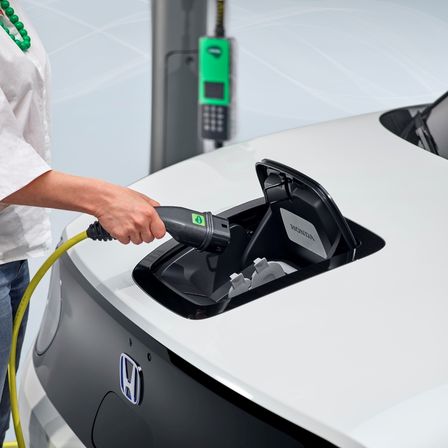 Nahaufnahme einer Frau, die Ladekabel in Honda E Elektroauto einsteckt