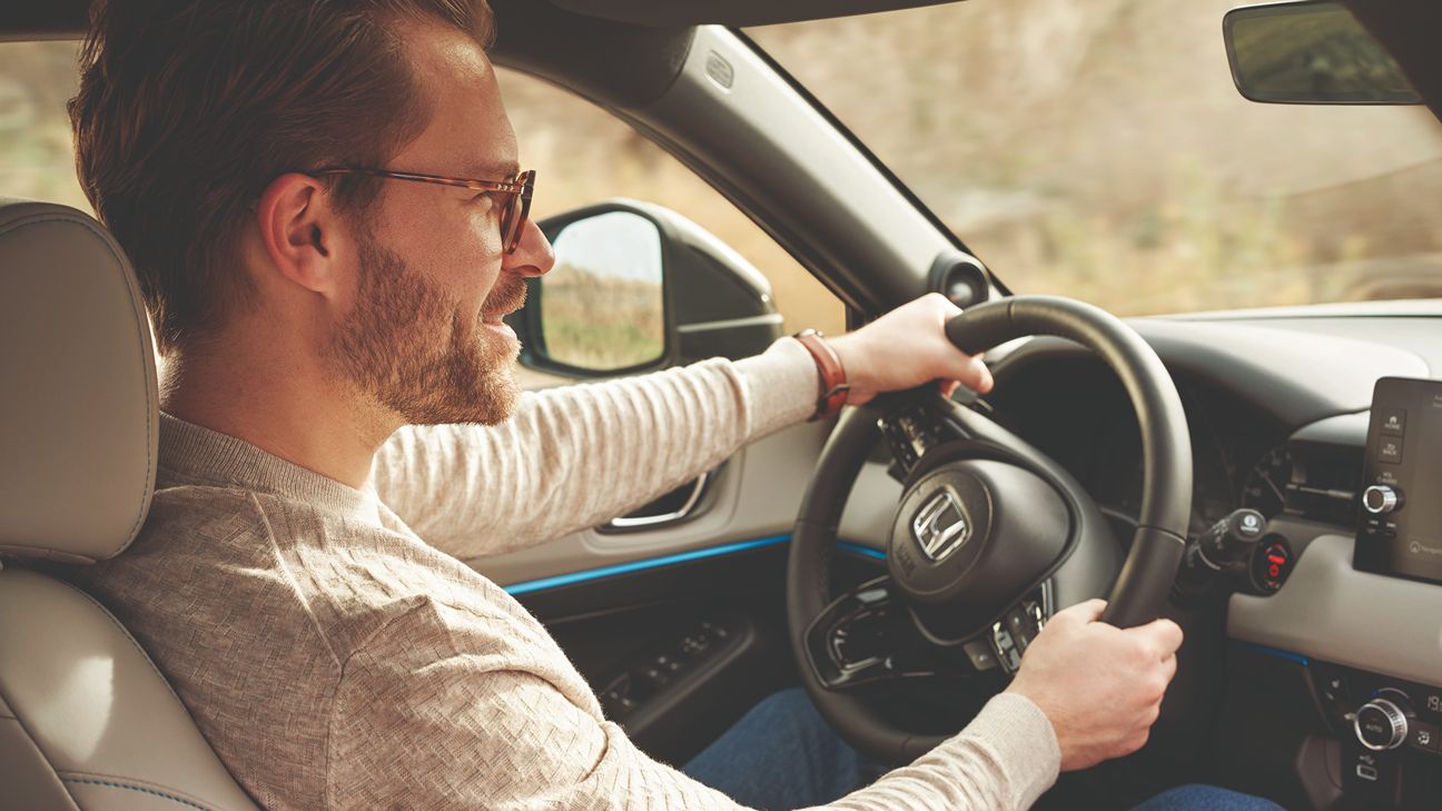 Mann mit Brille, der ein Honda Auto fährt