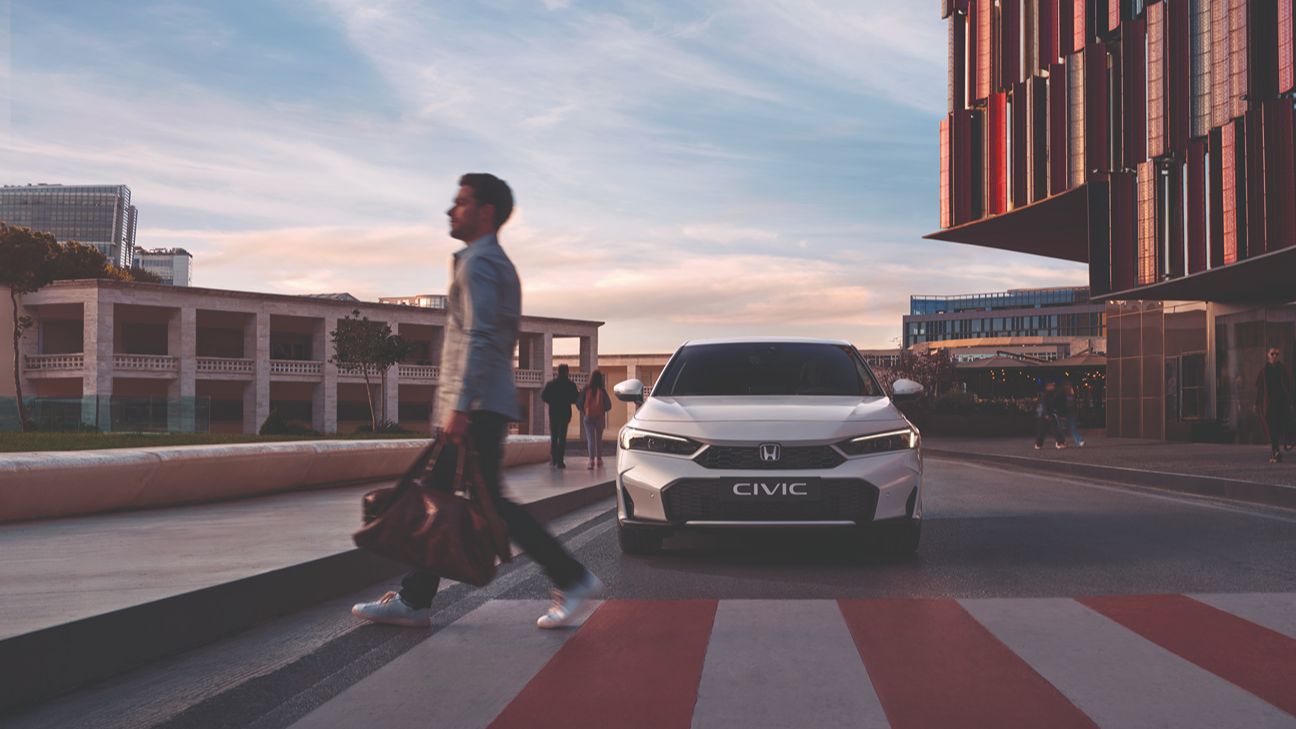 Mann überquert die Straße, weißer Honda Civic im Hintergrund