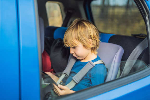 Junge, der bei einer Autofahrt ein Spiel auf seinem Tablet spielt