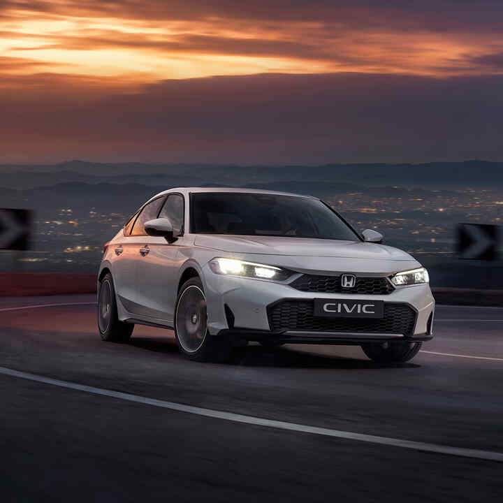 Honda Civic Hybrid in Bewegung auf einer Autobahn in der Dämmerung.