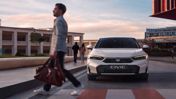 Ein Honda Civic Hybrid nähert sich einem Mann vor einem Fußgängerüberweg.