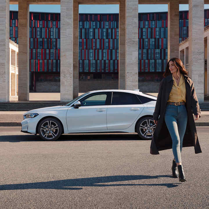 Eine Frau geht vor dem Civic Hybrid.