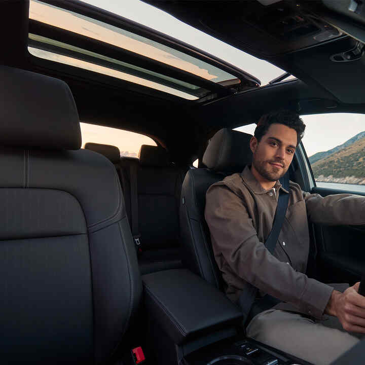 Innenaufnahme des Civic Hybrid, mit einem Mann am Steuer und fokus auf dem offenen Panoramadach.