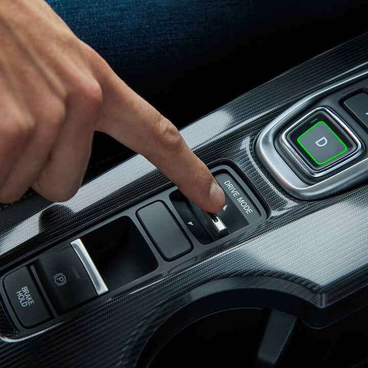 Nahaufnahme einer Person im Inneren des Civic Hybrid, die den Fahrmodus des Fahrzeugs einstellt.