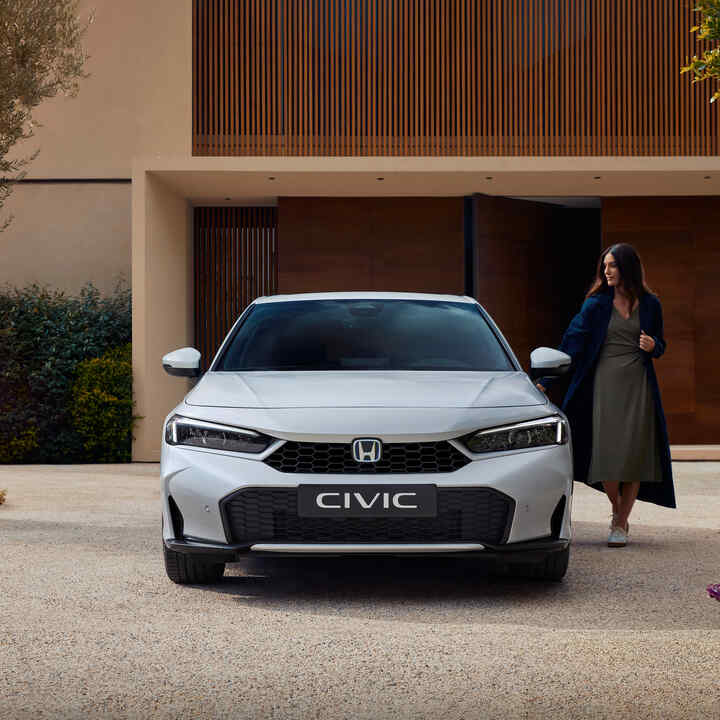 Frontalaufnahme eines Civic Hybrid, dessen Tür von einer Frau geöffnet wird.
