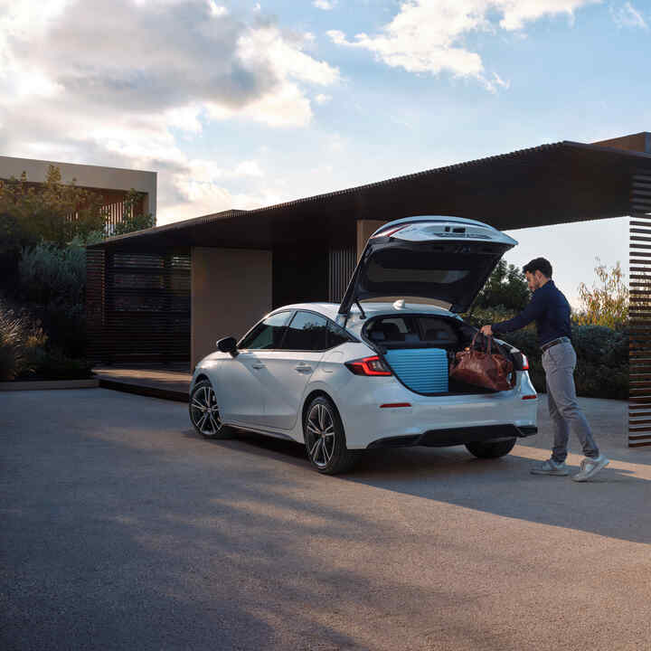 Eine Person, die Gepäck in den Kofferraum des Civic Hybrid packt.