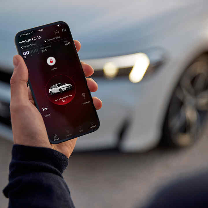 Eine Person hält ein Smartphone mit der My Honda+ App auf dem Bildschirm.