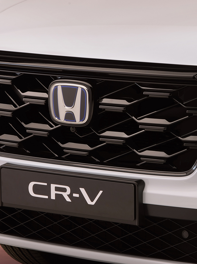 Nahaufnahme des Honda CR-V-Frontgrills mit schwarzem Wabenmuster, Honda-Logo in der Mitte und dem Modellnamen CR-V darunter.