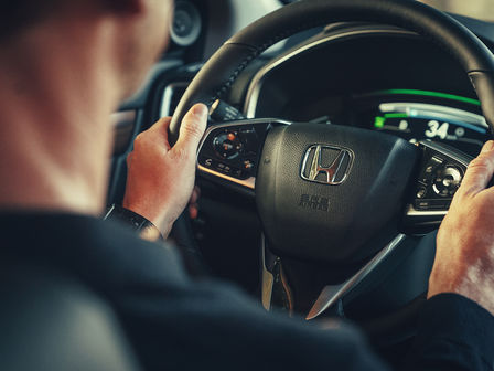 Honda CR-V Hybrid, Nahaufnahme einer Person mit den Händen am Lenkrad.