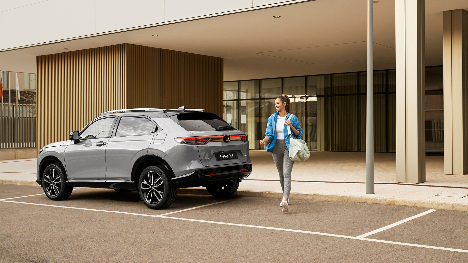Eine Frau läuft neben einem geparkten HR-V. 