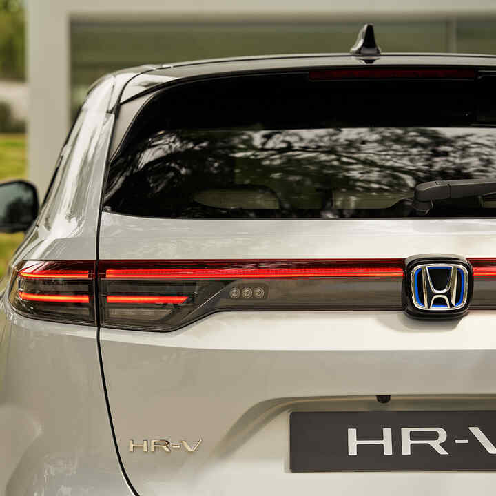 Ein Paar geht neben dem HR-V, der vor einem Gebäude geparkt ist. 