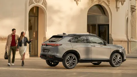 Seitenansicht des Honda HR-V vor einem Hotel, mit vorbeigehendem Paar 