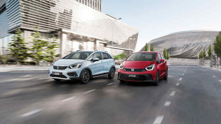 Ein Honda Jazz Hybrid und ein Honda Jazz Crosstar fahren nebeneinander in einer Stadt.
