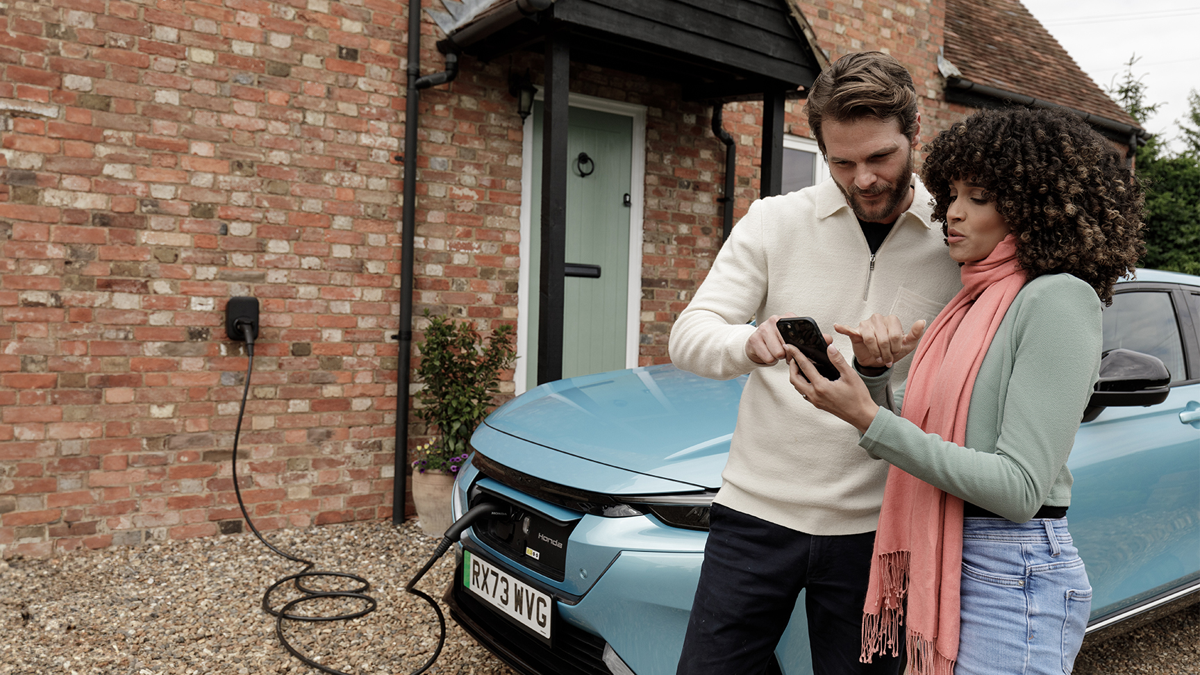 Model hält ein Handy mit Close up auf Hona E charging system