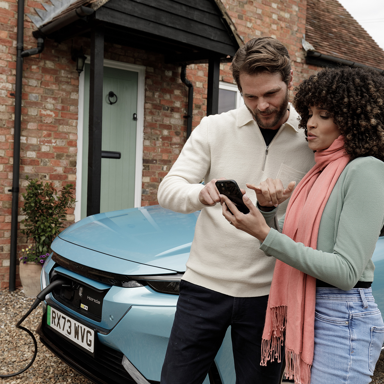 Model hält ein Handy mit Close up auf Hona E charging system