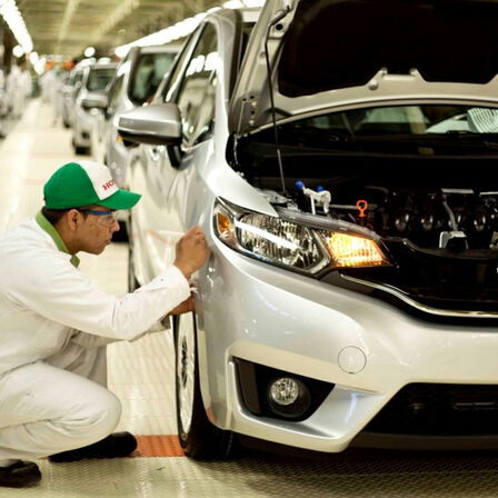 Honda Mechaniker bei der Arbeit in einem Werk an einem Fahrzeug.