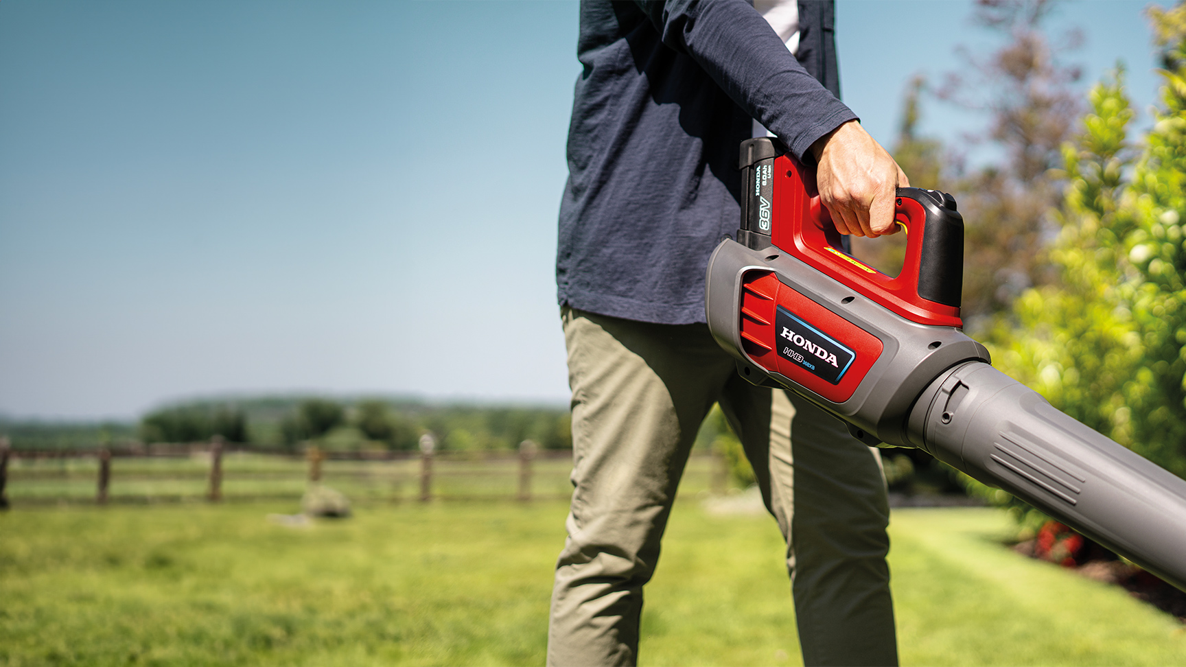 Mann mit Akku-Laubbläser in einem Garten.