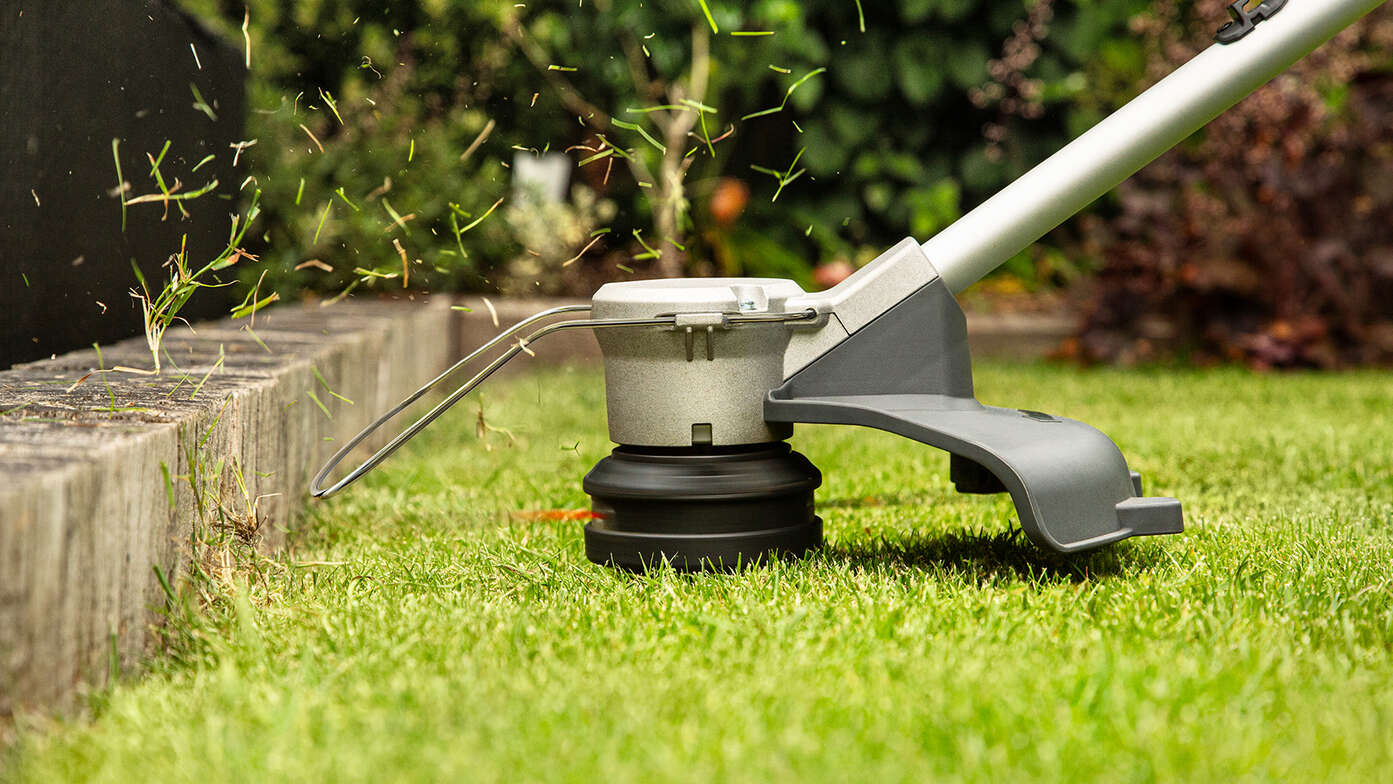 Honda Akku-Rasentrimmer im Einsatz an einer Rasenkante in einem Garten.