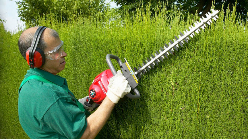 Mann mit Heckenschere und Kopfhörer mit Geräuschunterdrückung