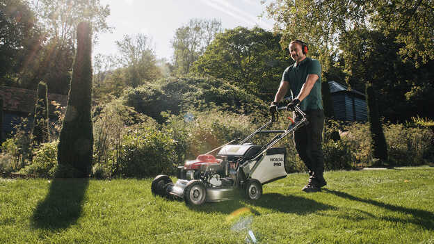 Mann in einem Garten beim Schieben eines Honda HRH