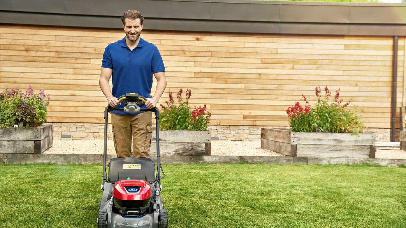 Mann in einem Garten beim Schieben eines Honda HRX