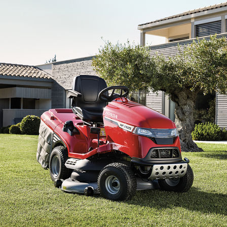 Dreiviertelfrontansicht eines Honda Traktors in einem Garten mit Haus im Hintergrund
