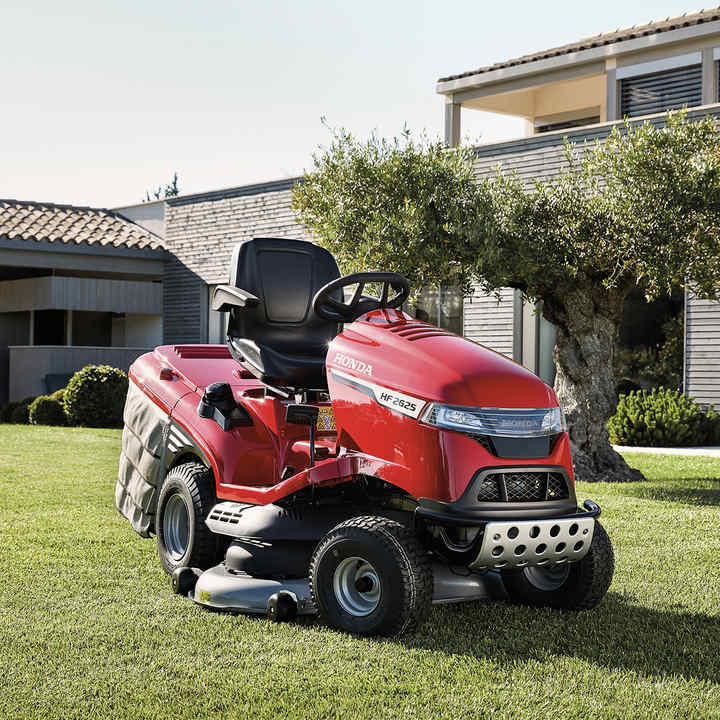 Dreiviertelfrontansicht eines Honda Traktors in einem Garten mit Haus im Hintergrund