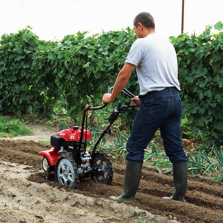 Mann mit Motorfräse auf einem Feld