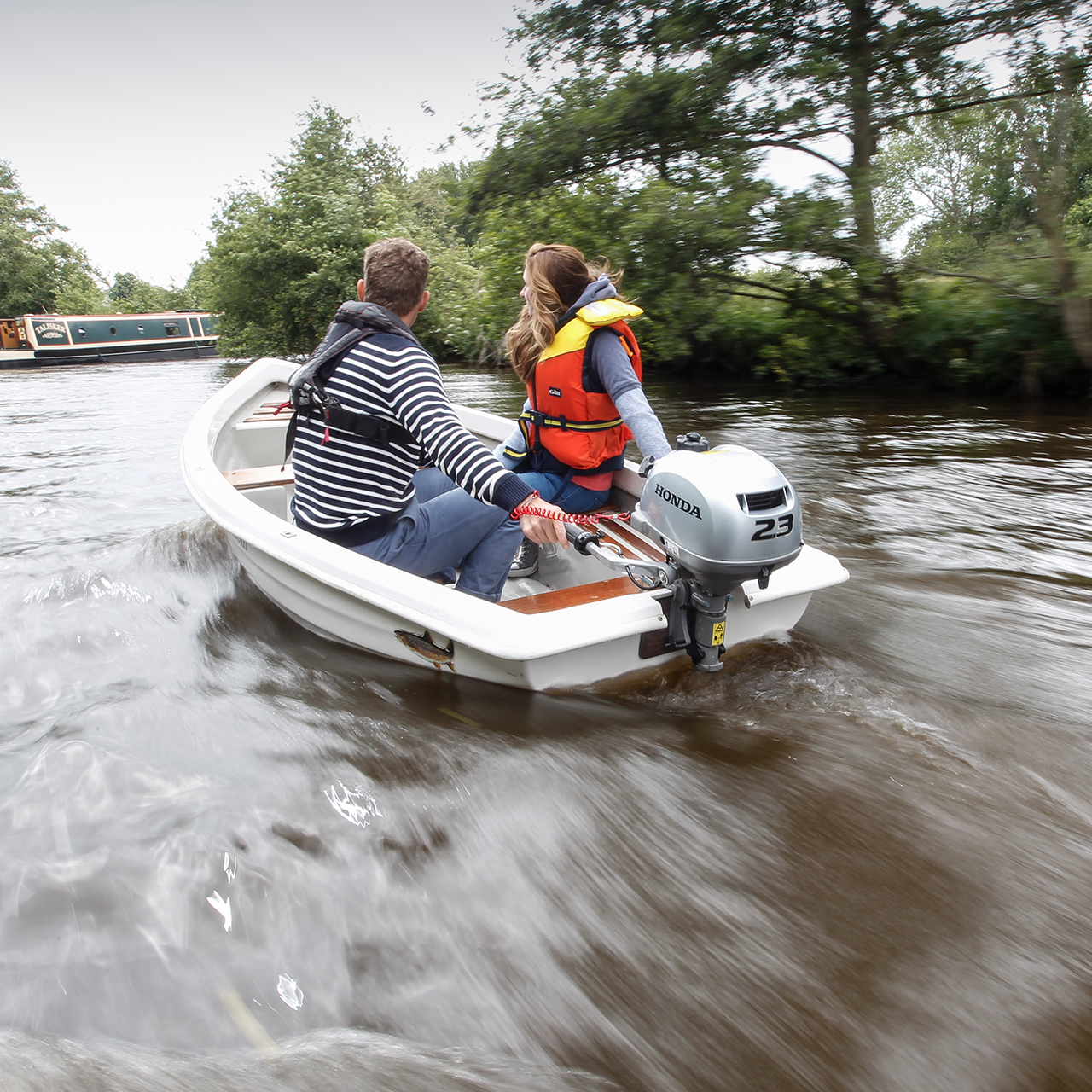 Zwei Personen in einem Boot, das den BF2.3-Motor verwendet, neben einem Kanalboot.