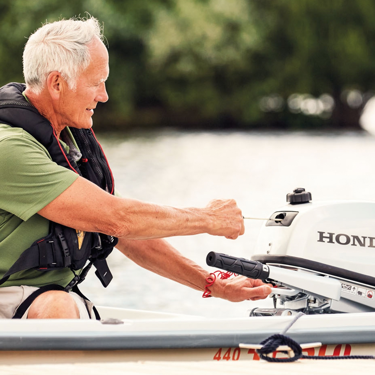 Ein Mann auf einem Boot startet einen Honda BF5-Motor.