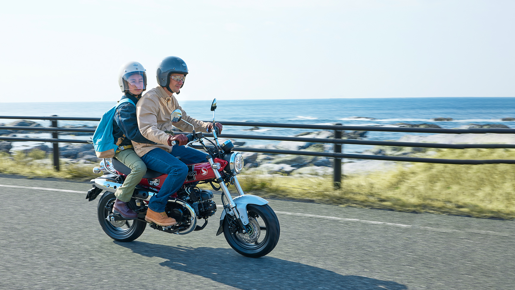 Honda Dax 125 auf einer Küstenstraße mit Fahrer und Sozius