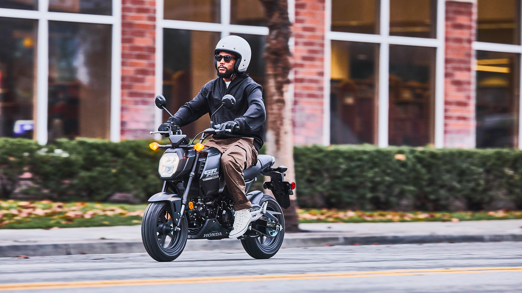 MSX125 Grom in Schwarz, geparkt mit Fahrern im Gespräch