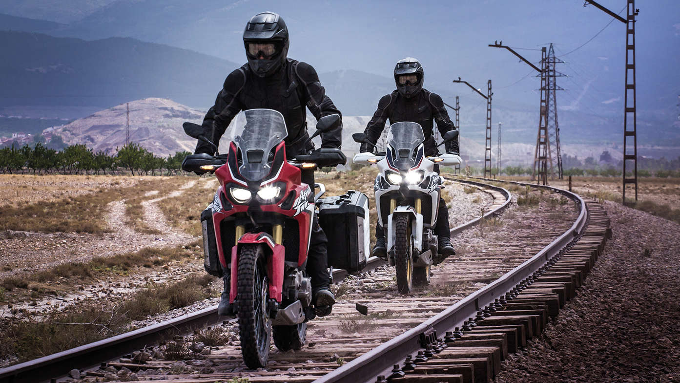 Zwei Honda Africa Twins bei der Fahrt entlang einer Eisenbahnstrecke