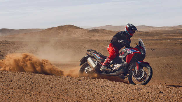 Model auf einem CRF1100L Africa Twin-Motorrad in einer Wüste.