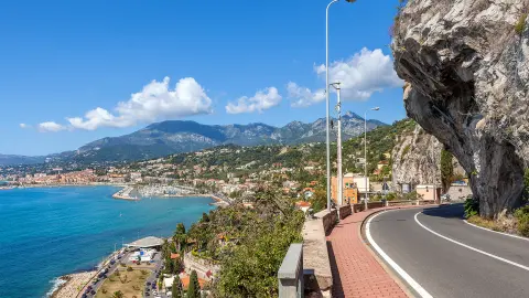 Malerische Straße unter blauem Himmel entlang der Mittelmeerküste im französisch-italienischen Grenzgebiet.