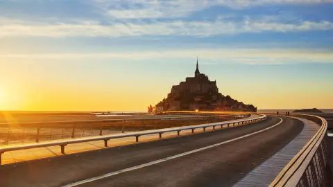 Straße zum Mont-Saint-Michel bei Sonnenuntergang, Normandie, Frankreich.