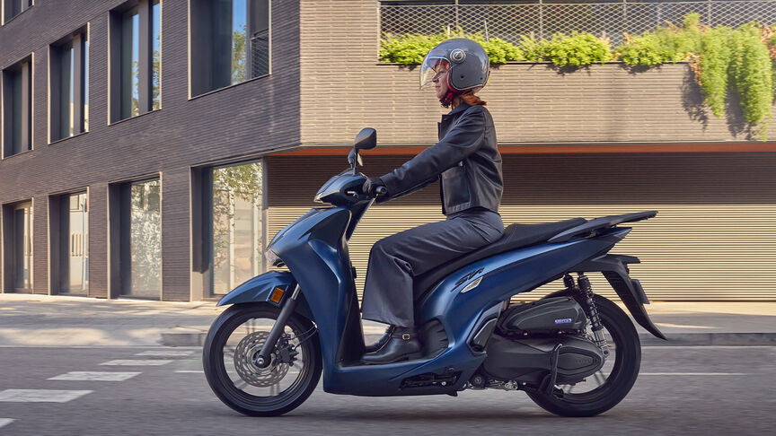 Frau auf einem Honda SH350i in der Stadt, Seitenansicht.