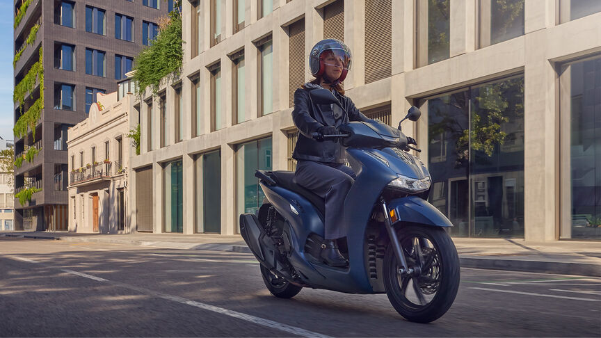 Frau auf einem Honda SH350i in der Stadt, Seitenansicht.