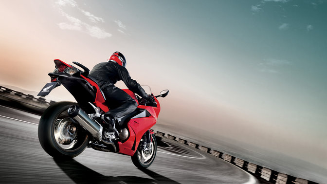 3/4-Frontansicht eines schwarzen Honda SH Mode-Motorrollers mit Fahrer. Nach rechts weisend (auf der Straße).