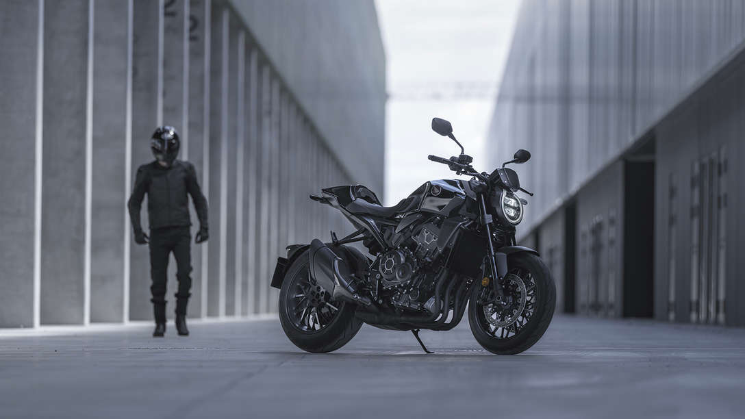 Honda CB1000R Black Edition – Mann steht zwischen Gebäuden neben dem Motorrad auf der Straße