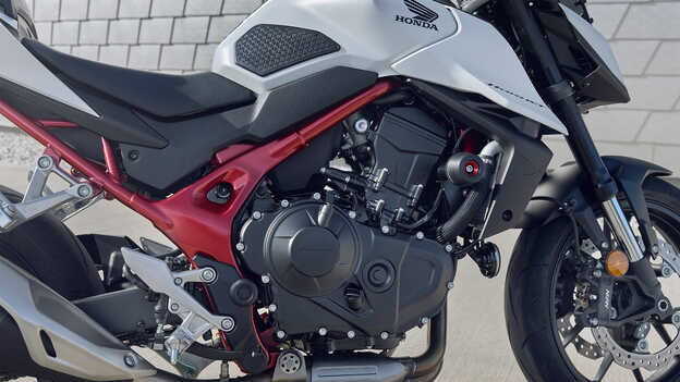Honda CB750 Hornet mit Mann, der sich an ein Gebäude lehnt.