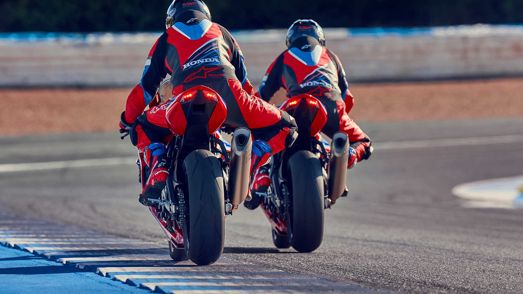 Honda CBR1000RR-R Fireblade auf der Rennstrecke mit zwei Fahrern, Heckansicht. 