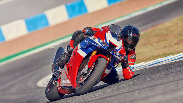 Honda CBR1000RR-R Fireblade mit Fahrer in Bewegung auf der Rennstrecke beim Beschleunigen aus der Kurve heraus.