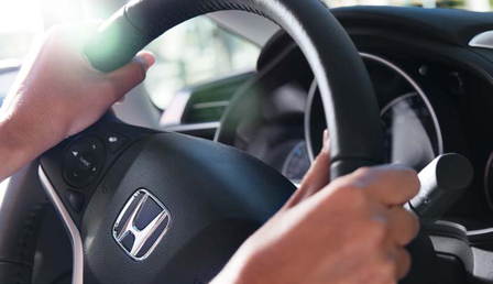 Nahaufnahme einer Person mit den Händen am Honda-Autolenkrad