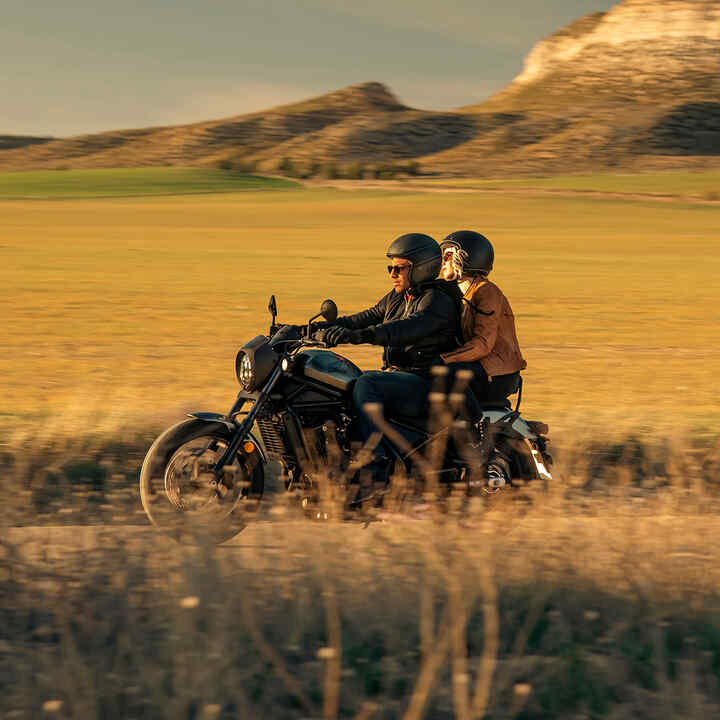 CMX1100 Rebel with rider and pillion on road at dusk