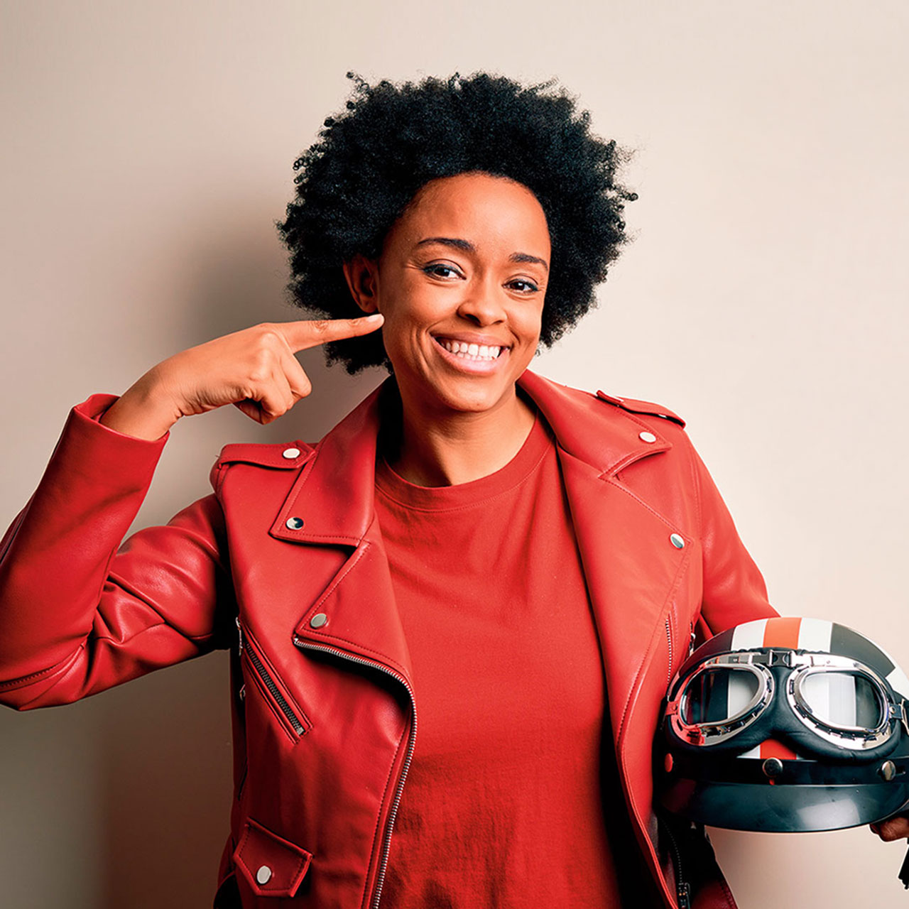 Studioaufnahme einer Frau mit Motorradhelm in der Hand.