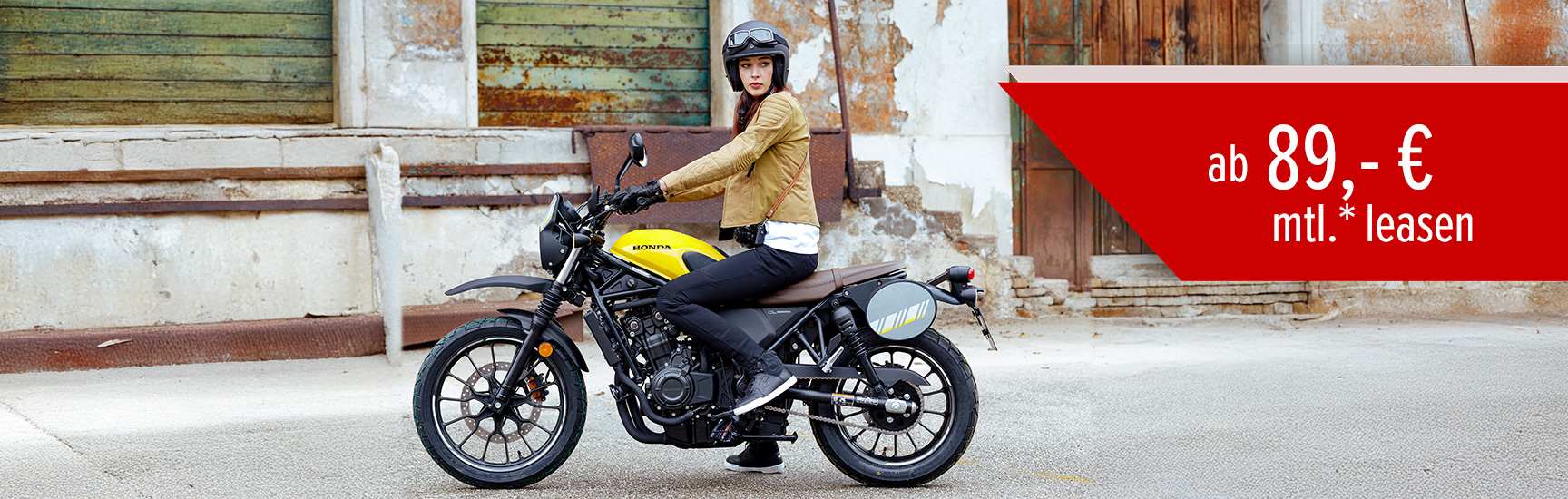 Ein Frau sitzt auf einer Honda CL500 vor einem alten Gebäude.